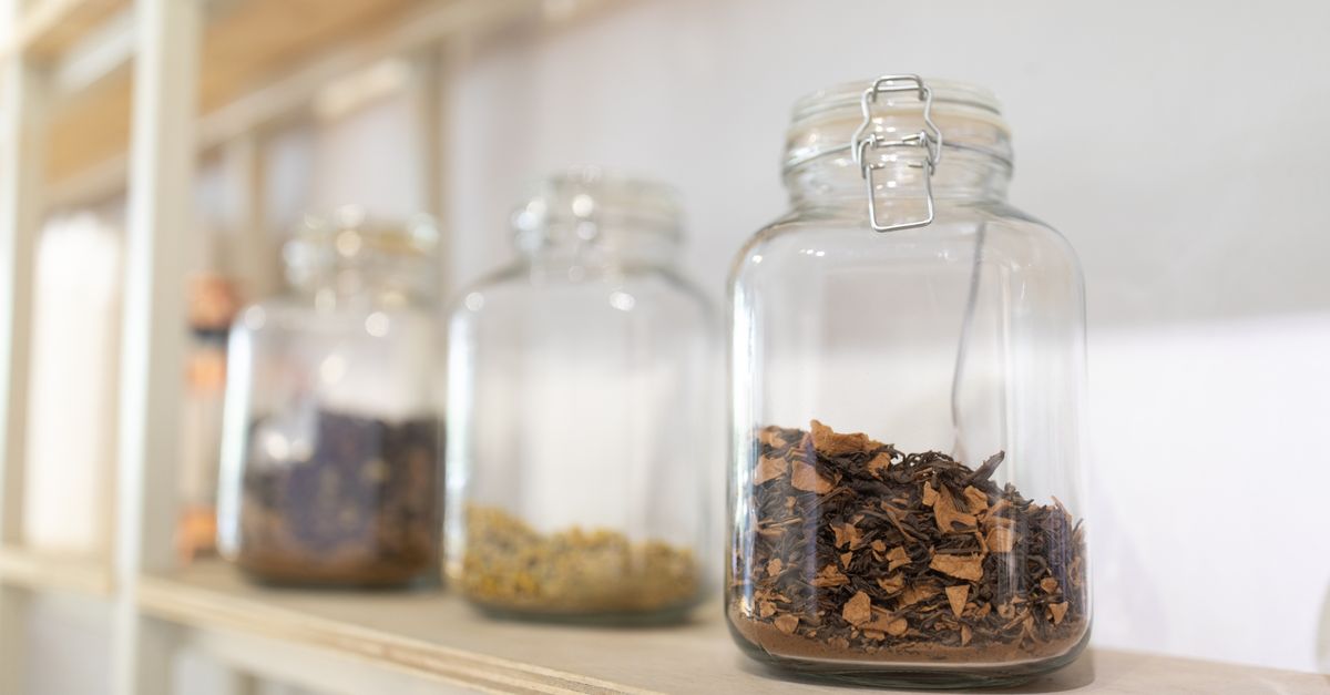 Wooden shelf with glass jars of spices, grains, and preserved foods