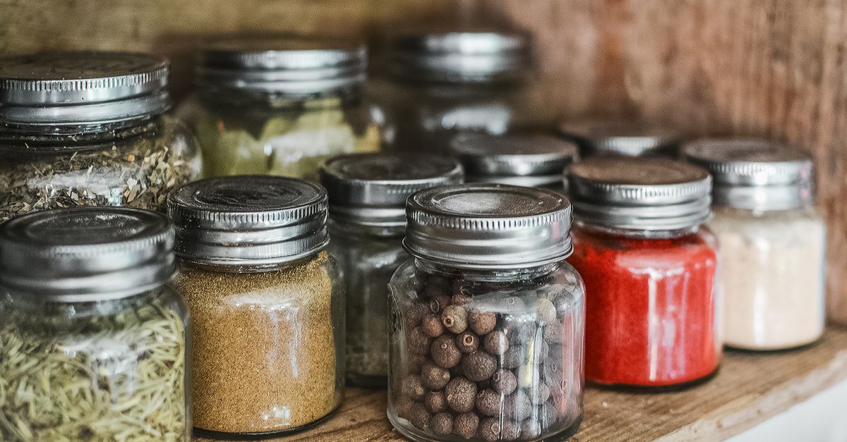 Estante de madera con frascos de vidrio de especias, granos y alimentos en conserva